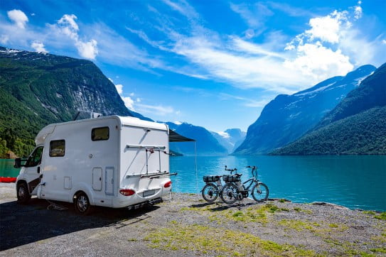 Campervan and bikes by mountains and lake. 