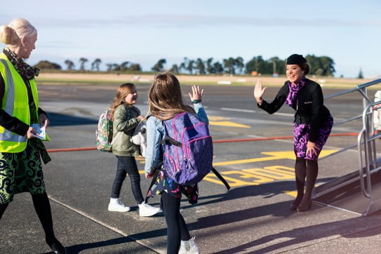 Children waving goodbye leaving an aircraft. 