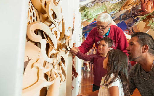 Visitors admiring wood carvings and artwork at Te Papa Museum, Wellington
