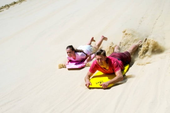 Sandboarding down the sand dunes at Te Paki in Northland, New Zealand. 