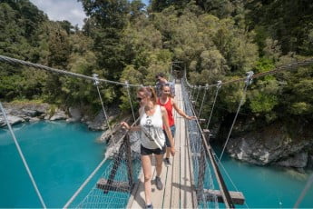 Friends crossing the swing bridge, Hokitika River, West Coast, NZ
