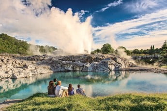 A family sitting at the Blue Lake, watching geysers in Te Puia Rotorua.